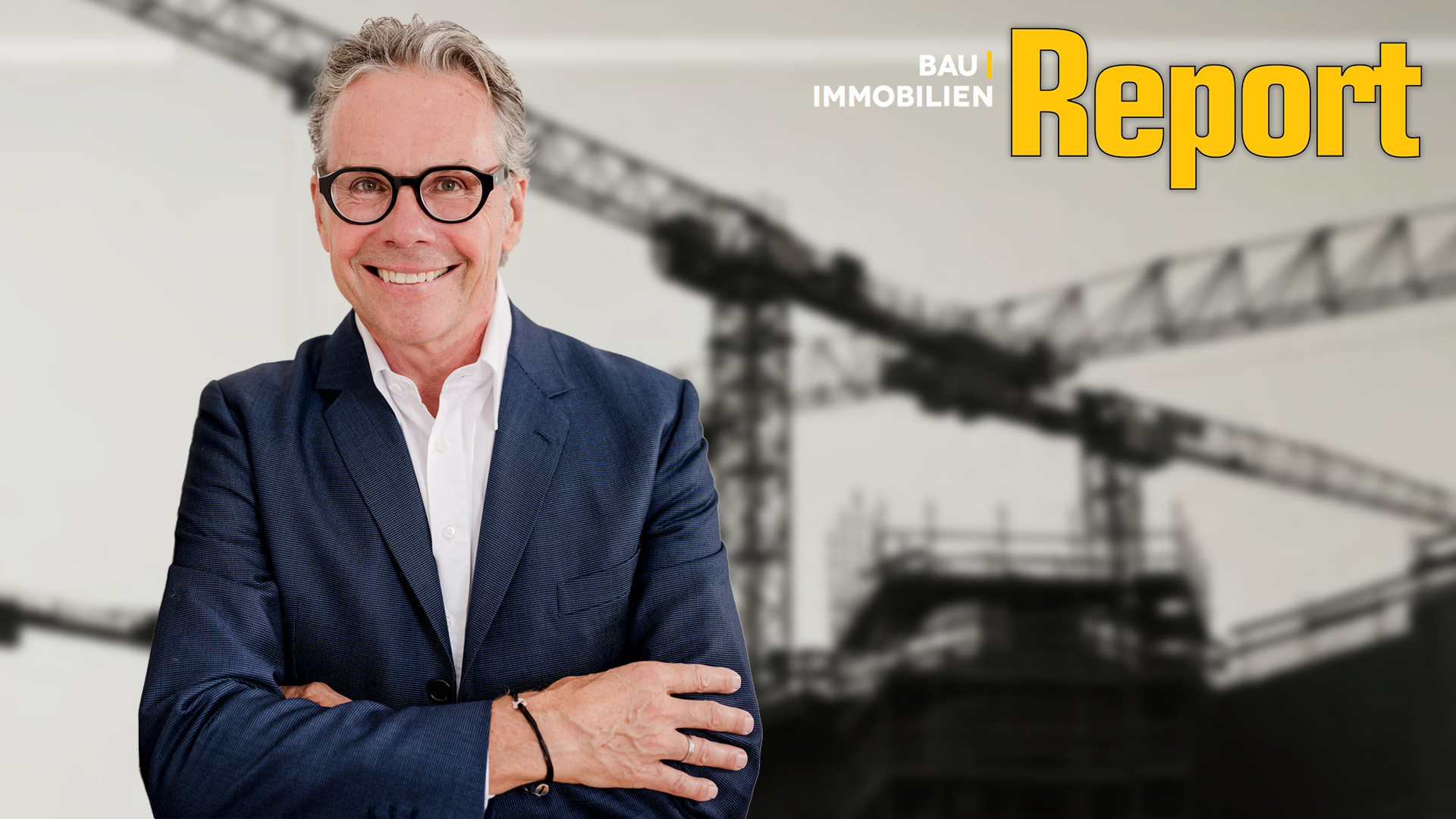 Ein Mann in einem Anzug steht links im Bild. Im Hintergrund sind Kräne zu sehen und oben rechts ist das Logo des Bau & Immobilien Reports.